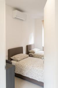 two beds in a room with white walls at Fiera Milano 110mq 3 Bedroom Apartment in Senago