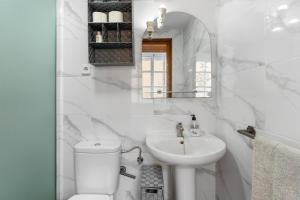 a white bathroom with a toilet and a sink at Taklägenhet Med Stor Terass in Fuengirola +12 photos