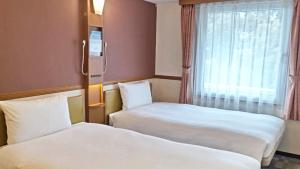 热海热海站前东横旅馆(Toyoko Inn Atami Ekimae) 的有两张床和一扇窗户的酒店房间