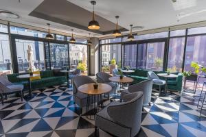 Un restaurante con sofás, mesas y ventanas. en Stay In Luxury at The Pullman, en Ciudad del Cabo