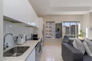 una cocina con fregadero y un sofá en una habitación en Stay In Luxury at The Pullman, en Ciudad del Cabo 13 fotos más
