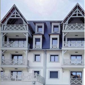 a white apartment building with white balconies and a blue roof at Refuge Chaleureux et Lumineux, Wifi, Balcon, Parking au coeur de Deauville in Deauville