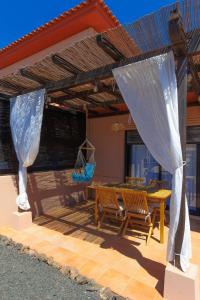 un patio con tavolo e sedie in legno sotto un pergolato di Alinico House a Majanicho