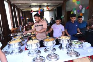 a group of men standing around a table with food at AMARJAGAT HOTEL & RESTAURANt in Rudraprayāg