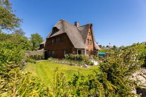 a large brick house with a thatched roof at Appartement Salzwiese in Tinnum