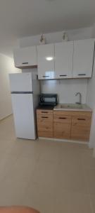 a kitchen with a white refrigerator and wooden cabinets at Condo Santosha on the beach in Pomorie +2 photos