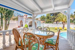 Un patio con mesa y sillas y una piscina. en Villa Sophie, en Denia