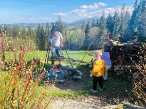 a man and two children standing around a campfire at Willa Pachówka - tam, gdzie natura spotyka się z nowoczesnością in Bukowina Tatrzańska