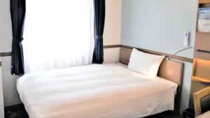 a small bed in a room with a window at Toyoko Inn Tokyo Korakuen Bunkyokuyakusho Mae in Tokyo