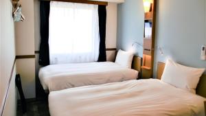 two beds in a room with a window at Toyoko Inn Tokyo Korakuen Bunkyokuyakusho Mae in Tokyo