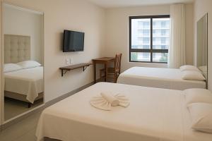 une chambre d'hôtel avec deux lits et un miroir dans l'établissement Ilusion Flat -Natal, à Natal 38 autres photos