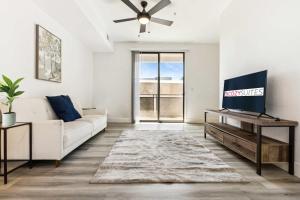 ein Wohnzimmer mit einem weißen Sofa und einem Fernseher in der Unterkunft Glendale CozySuites - Westgate with pool 10 in Glendale