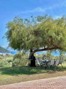 a picnic table under a tree with chairs under it at Perl's Apartment in Póndi