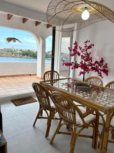 a dining room with a table and chairs with a view of the ocean at El Mirador de NaLi - accès direct à la plage in Arenal d'en Castell