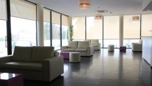 a waiting room with couches and tables and windows at Hotel Monte Lírio in Espinho