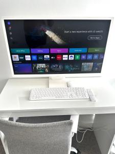a computer monitor sitting on a desk with a keyboard at City Centre Penthouse Bedroom in Birmingham +4 photos