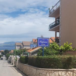 a blue sign on a street next to a building at room&4you in Supetar
