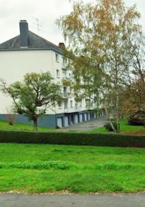 a large white house with trees in the grass at Le Lodge in Fougères