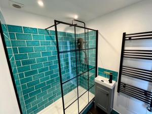 a bathroom with a glass shower with blue tiles at Warehouse Conversion Flat in London