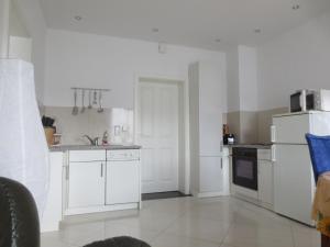 cocina con armarios blancos y nevera blanca en Ferienwohnung Creutzer, en Gottscheina