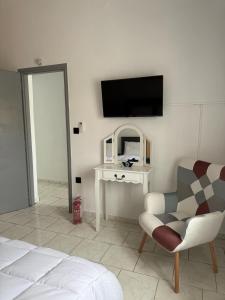 a bedroom with a bed and a chair and a tv at STYILEL apartment MIlos 2 in Triovasálos