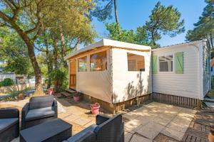 une petite maison assise sur une terrasse avec des chaises dans l'établissement Mh 25 Les Genêts Ronce les bains, à La Tremblade