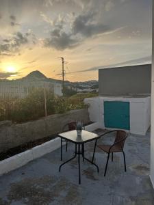 a table and two chairs on a patio with the sunset at STYILEL apartment MIlos 2 in Triovasálos