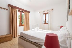 ein Schlafzimmer mit einem weißen Bett und einem roten Stuhl in der Unterkunft Borges in Son Serra de Marina