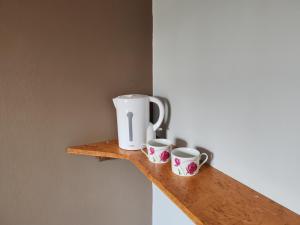 a coffee maker and two cups on a wooden shelf at L'Etape in Pont-d'Ouilly