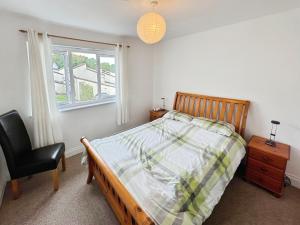 Thistle Cottage في Wootton Bridge: غرفة نوم بها سرير وكرسي ونافذة