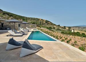 a swimming pool with chaise lounge chairs next to a mountain at Aegean Hestia Luxury Villa of Paros in Kampos Paros +69 photos