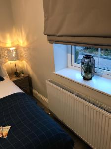 a bedroom with a bed and a window with a vase at Flat 1 Helena House 1-Bed Sleeps 2 Garden in Reading