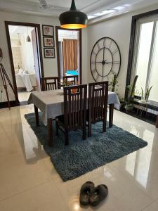 uma sala de estar com uma mesa e um relógio na parede em Green & Ivory Homestay em Gurgaon