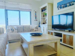 Una sala de estar con un sofá y una mesa con televisión. en Bluebird Empire Penthouse, en Muizenberg 55 fotos más
