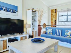 Una sala de estar con un sofá azul y un televisor. en Bluebird Empire Penthouse, en Muizenberg