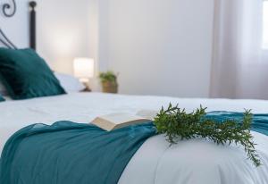 a book on a bed with a plant on it at Apartamentos Collado Playa Valdelagrana in El Puerto de Santa María