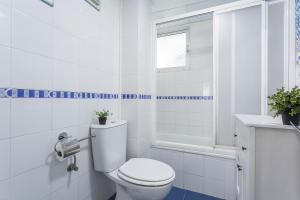 a white bathroom with a toilet and a sink at Apartamentos Collado Playa Valdelagrana in El Puerto de Santa María +35 photos