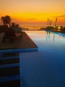 een zwembad met een zonsondergang op de achtergrond bij The gallery condominium Ben in Jomtien Beach