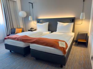 a hotel room with two beds and a chair at Vienna House Easy by Wyndham Bucharest Airport in Otopeni