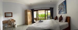 a bedroom with a large bed and a table at Holiday Guest House in Amed