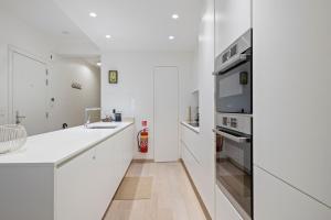 a white kitchen with a sink and a stove at Evasion mer à Ostende in Ostend +14 photos