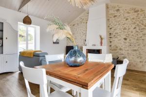a dining room with a table with a vase on it at Piscine chauffée, jardin, magnifique villa pour 10 in La Guérinière