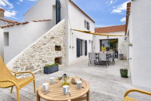 a patio with a table and chairs and a building at Piscine chauffée, jardin, magnifique villa pour 10 in La Guérinière