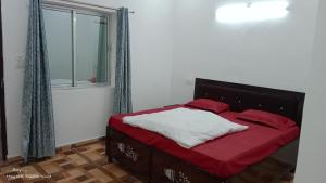 a bedroom with a bed with red sheets and a window at Kedar view inn in Phata