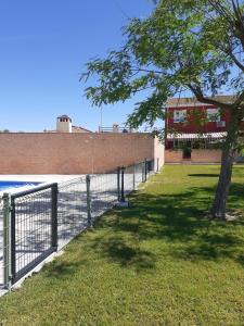 a fence with a tree next to a wall at Casa El Garrobo in El Garrobo