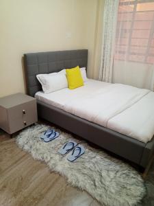 a bed with slippers on a rug in a bedroom at Gardenview Homes -2 Bedroom Apartment along Nyeri-Nanyuki Road -Kingongo in Nyeri