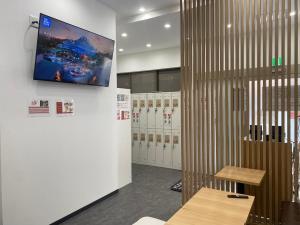 a locker room with lockers and a tv on the wall at guest house B in Osaka
