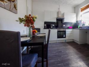a kitchen with a table with a vase of flowers at 12 Cornwallis Lodge Family Room 1 in Stoke on Trent +13 photos