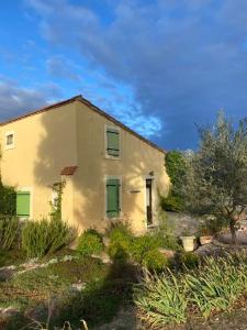 an old house with green shuttered windows and bushes at Domaine Saint Antoine in Rieux-Minervois