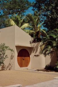 a white building with a wooden door in front of trees at Mihira Home in Ahangama